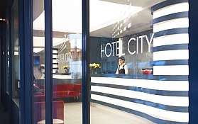 Rezeption im Hotel City Moderne Hotelrezeption mit Mitarbeiterin und Blumenarrangement.